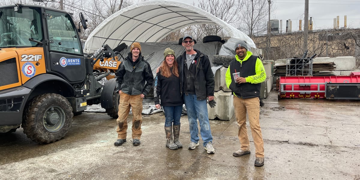 Snow removal team standing beside commercial snow plowing equipment