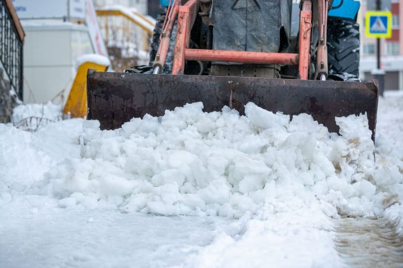 Commercial snow plow truck clearing a Troy MI parking lot during a storm